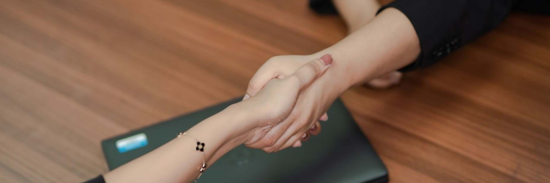 Two people shaking hands over a desk
